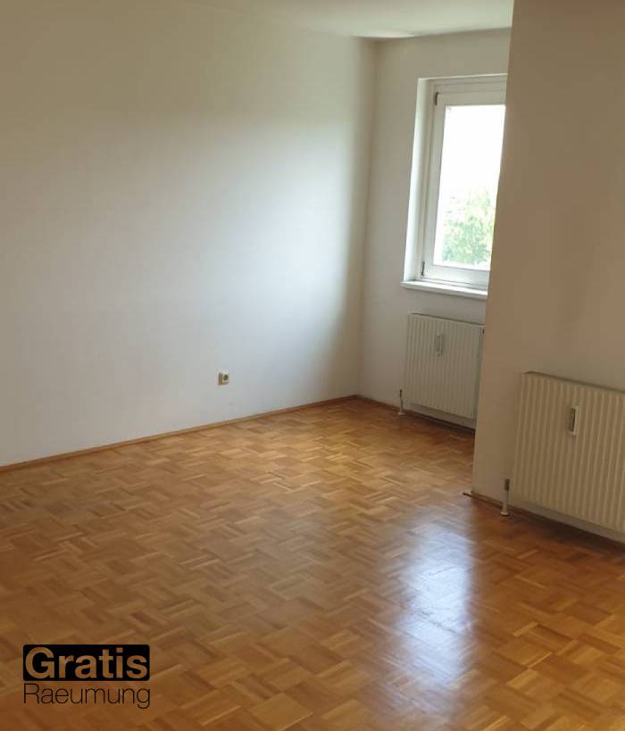 Zimmer in einem unmöblierten, leeren Haus; ein Fenster und zwei Heizkörper sind an der Wand sichtbar. 